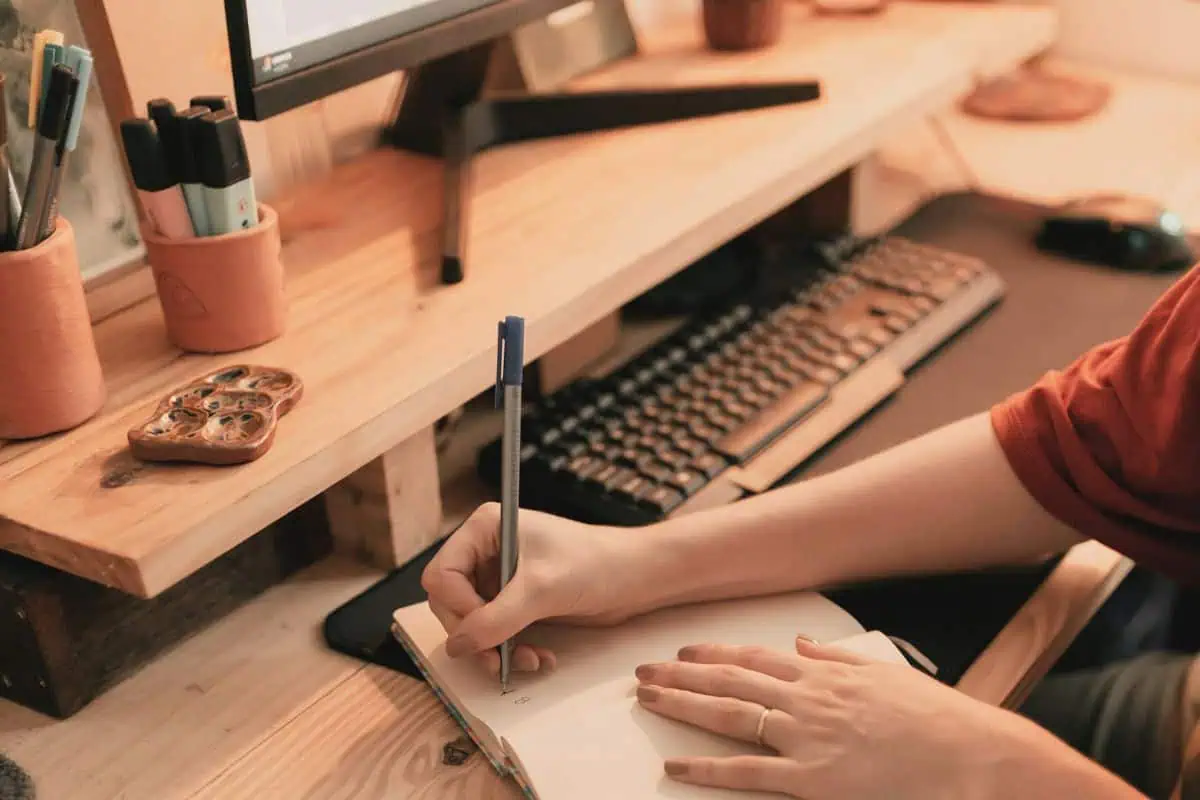 person writing in a notebook writing tools for writers wordista